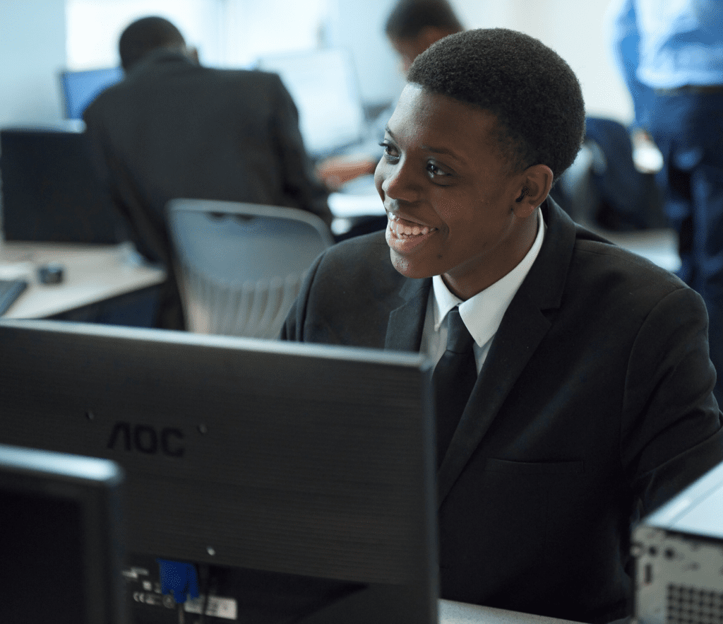 a young man in a suit is smiling while working on a computer